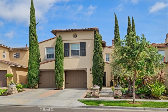 view of front of property featuring concrete driveway, a tiled roof, a garage, and stucco siding