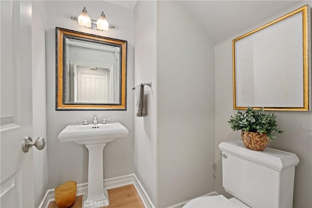 bathroom with toilet, baseboards, wood finished floors, and lofted ceiling