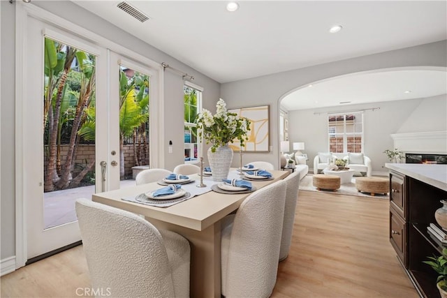 dining space featuring visible vents, arched walkways, light wood-style flooring, and french doors