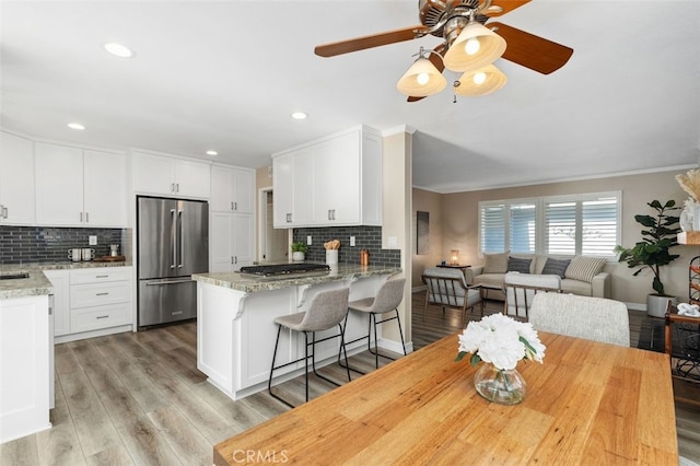18401 Goodwin Ln, Huntington Beach, CA 92646 - kitchen featuring backsplash, light wood-type flooring, light stone counters, a peninsula, and stainless steel appliances