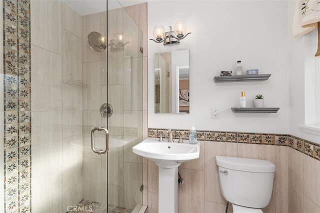 18401 Goodwin Ln, Huntington Beach, CA 92646 - bathroom featuring toilet, tile walls, a wainscoted wall, and a stall shower