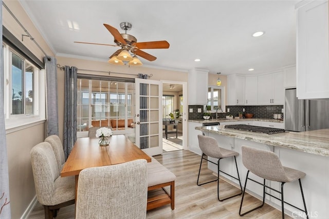 18401 Goodwin Ln, Huntington Beach, CA 92646 - interior space featuring light stone countertops, a kitchen breakfast bar, white cabinetry, appliances with stainless steel finishes, and backsplash