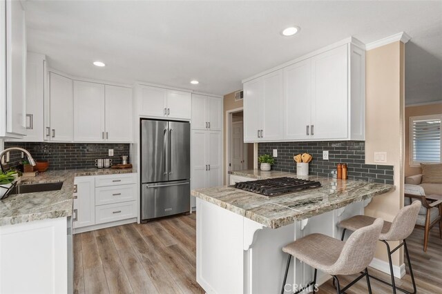 18401 Goodwin Ln, Huntington Beach, CA 92646 - kitchen featuring appliances with stainless steel finishes, a sink, a peninsula, light wood-style floors, and white cabinetry