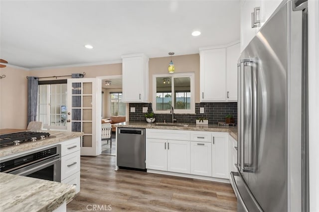 18401 Goodwin Ln, Huntington Beach, CA 92646 - kitchen with tasteful backsplash, a sink, white cabinets, stainless steel appliances, and light wood-style flooring