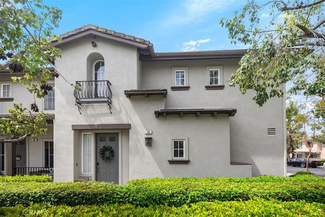 view of front of house featuring stucco siding and a balcony