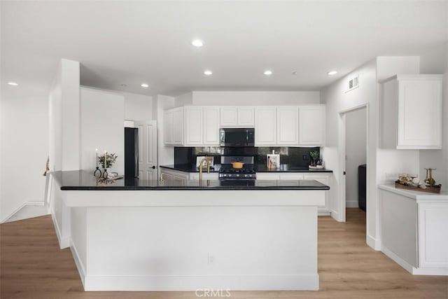 kitchen with appliances with stainless steel finishes, dark countertops, white cabinetry, recessed lighting, and tasteful backsplash