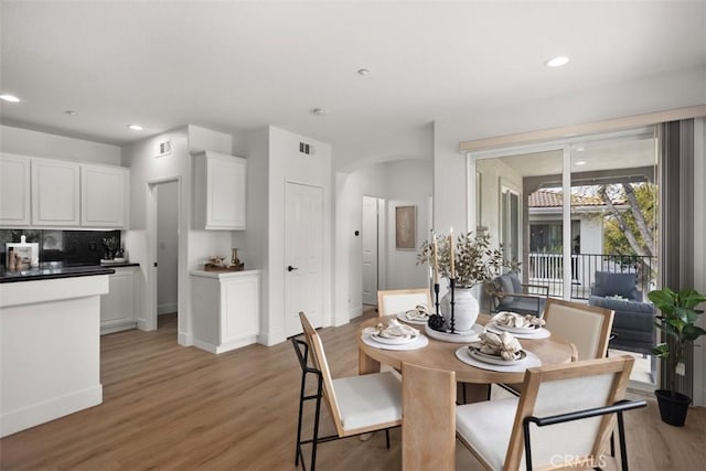 dining area with light wood-type flooring, arched walkways, recessed lighting, and baseboards