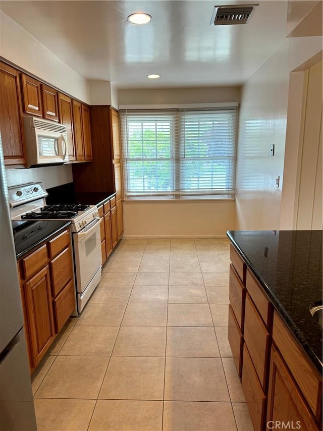 7940 Lena Ave, West Hills, CA 91304 - kitchen featuring white appliances, brown cabinetry, dark stone countertops, light tile patterned floors, and visible vents