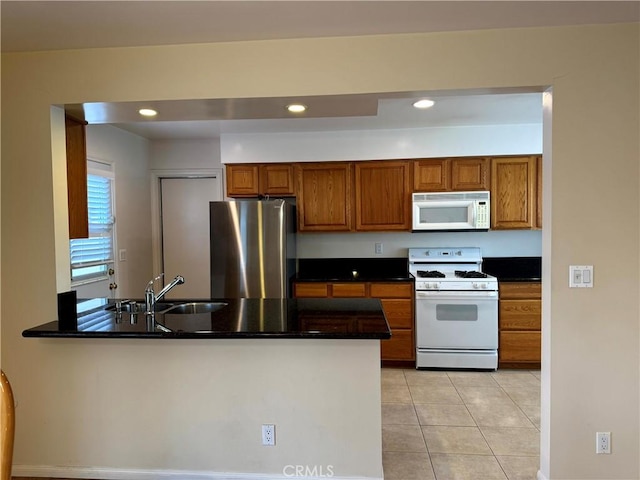 7940 Lena Ave, West Hills, CA 91304 - kitchen featuring brown cabinetry, dark countertops, a peninsula, recessed lighting, and white appliances