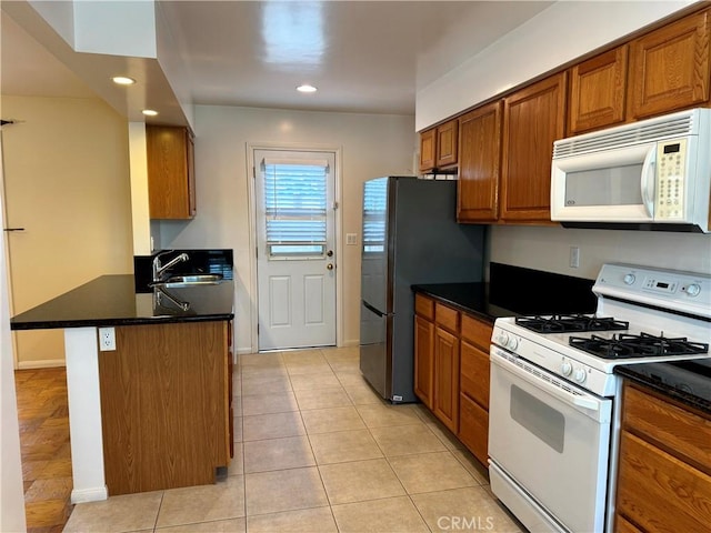 7940 Lena Ave, West Hills, CA 91304 - kitchen featuring white appliances, brown cabinets, dark countertops, and a peninsula