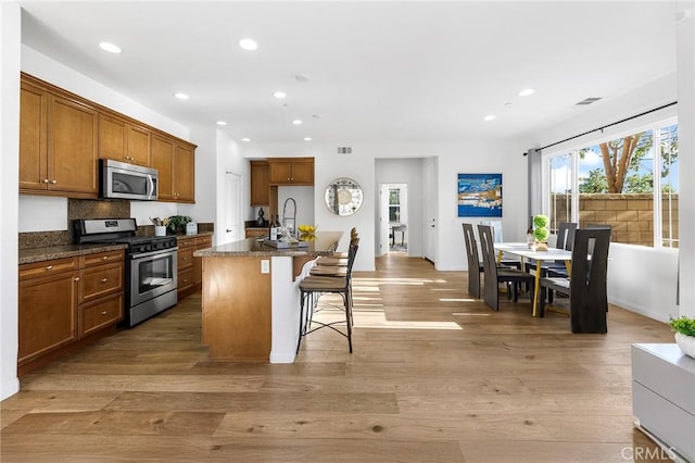 6410 Eucalyptus Ave, Chino, CA 91710 - kitchen with dark countertops, appliances with stainless steel finishes, brown cabinetry, and light wood finished floors