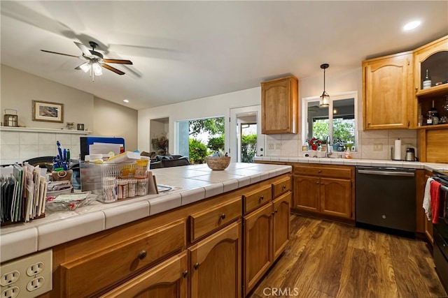 kitchen featuring decorative backsplash, dark wood-style floors, tile countertops, a ceiling fan, and dishwasher