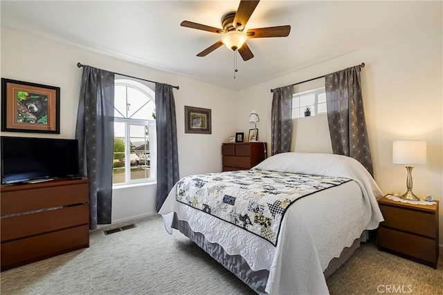carpeted bedroom with visible vents, a ceiling fan, baseboards, and multiple windows