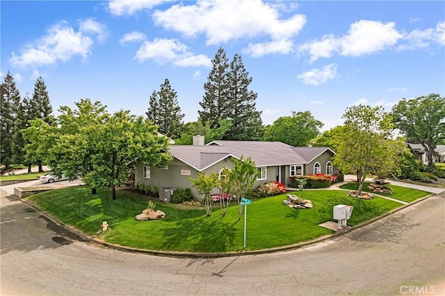 ranch-style home featuring a chimney, cooling unit, and a front yard