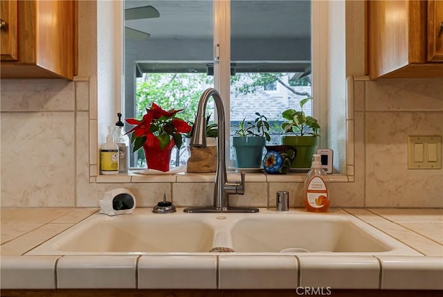 room details featuring brown cabinetry, a sink, and light countertops