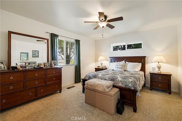 bedroom featuring visible vents, baseboards, ceiling fan, and light carpet