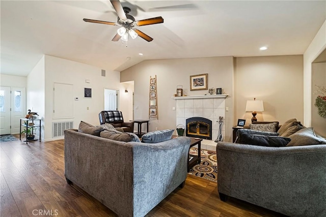 living area featuring a ceiling fan, visible vents, a tile fireplace, and dark wood-type flooring
