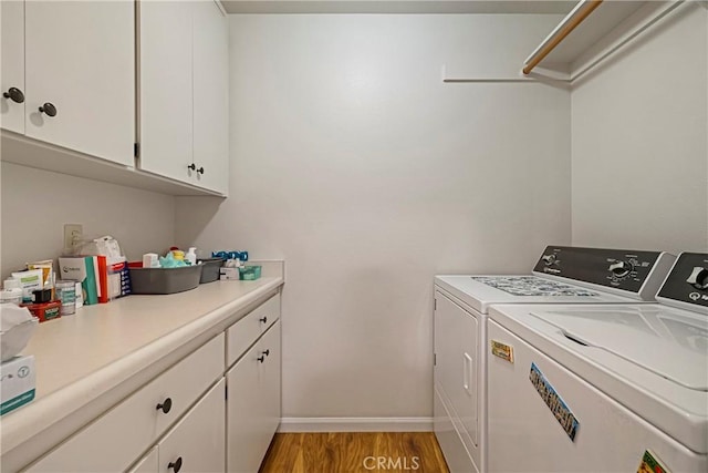 clothes washing area featuring independent washer and dryer, baseboards, light wood finished floors, and cabinet space