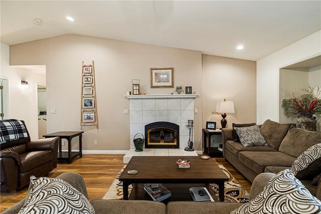 living area featuring a tiled fireplace, recessed lighting, lofted ceiling, and wood finished floors