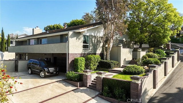 view of property with a garage, stucco siding, a chimney, driveway, and stairway