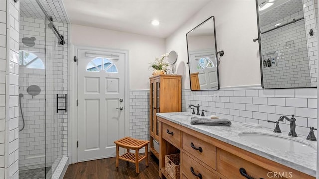12782 Periwinkle Dr, North Tustin, CA 92705 - bathroom featuring tile walls, a shower stall, wood finished floors, double vanity, and wainscoting