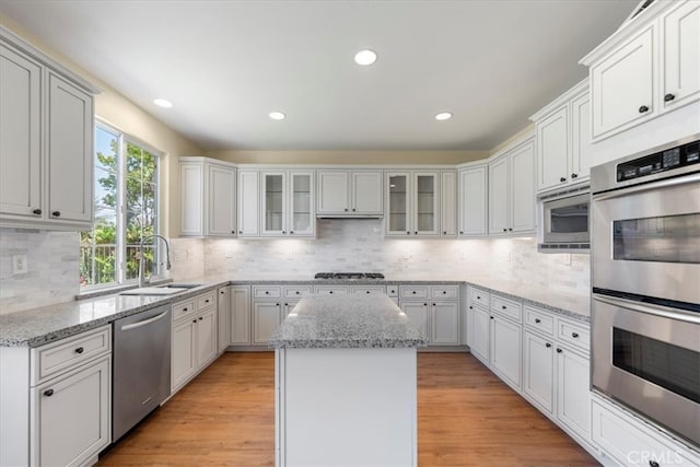 27020 Island Rd, Valencia, CA 91355 - kitchen with appliances with stainless steel finishes, backsplash, glass insert cabinets, light stone countertops, and recessed lighting