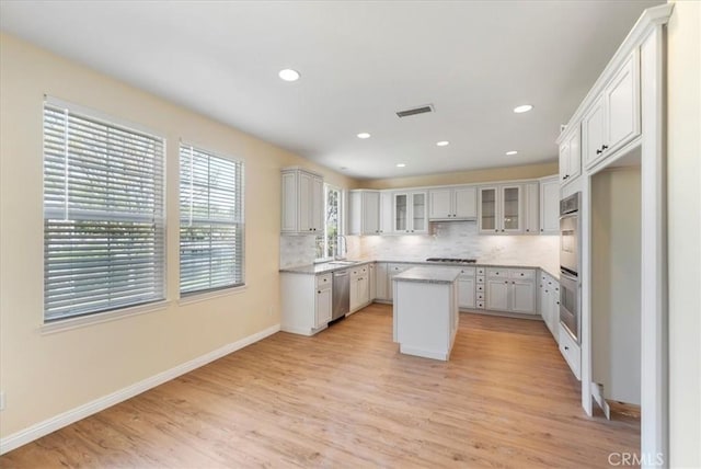 27020 Island Rd, Valencia, CA 91355 - kitchen with stainless steel appliances, a center island, light wood-style flooring, decorative backsplash, and recessed lighting
