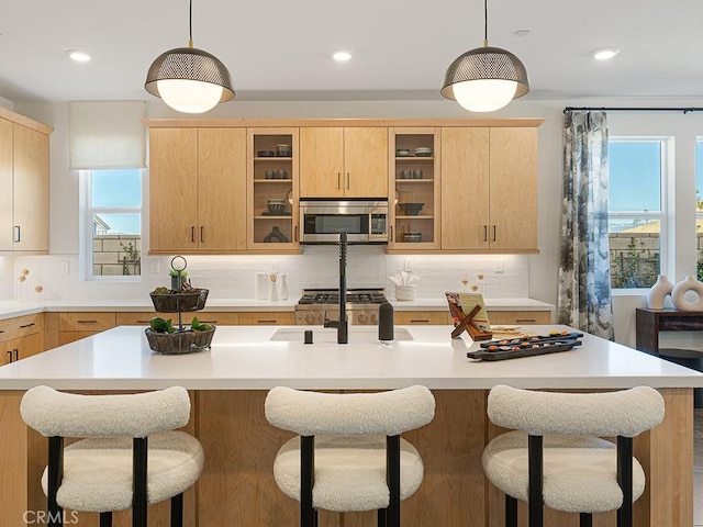 kitchen featuring light countertops, stainless steel microwave, and light brown cabinets