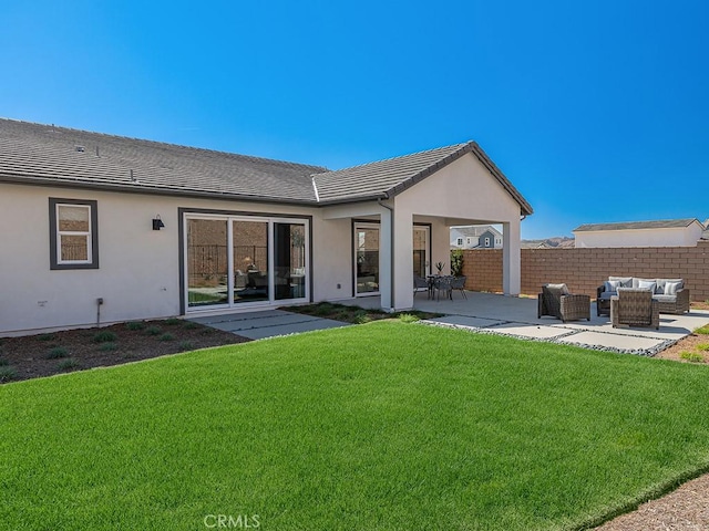 back of property with a tile roof, stucco siding, outdoor lounge area, a patio area, and a lawn