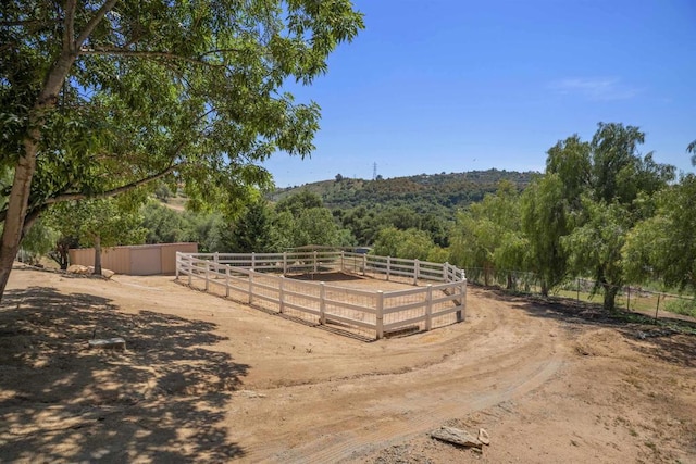 view of yard featuring a forest view, a rural view, fence, and an enclosed area
