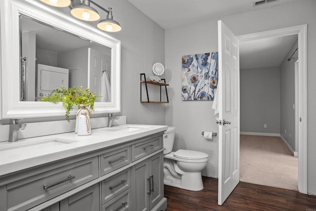 full bath featuring a sink, double vanity, toilet, and wood finished floors