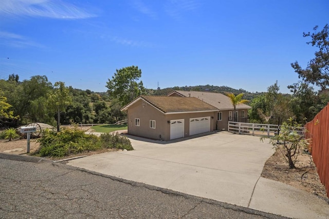 view of property exterior featuring fence, stucco siding, an attached garage, driveway, and a tile roof