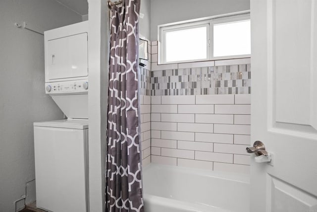 bathroom with stacked washer and clothes dryer and shower / bathtub combination with curtain
