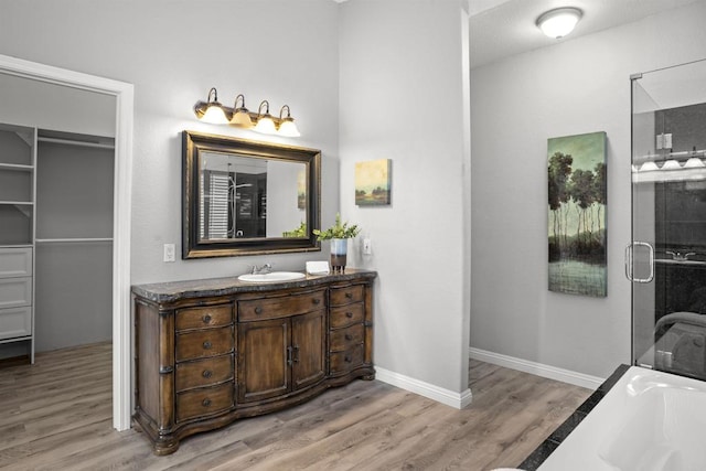 full bath featuring vanity, baseboards, a shower with shower door, and wood finished floors