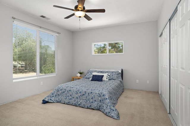 carpeted bedroom with a closet, a ceiling fan, visible vents, and multiple windows
