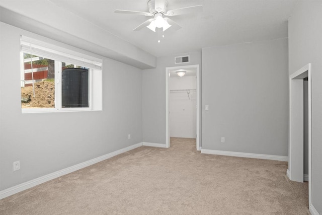 unfurnished bedroom featuring visible vents, a closet, light carpet, baseboards, and a spacious closet