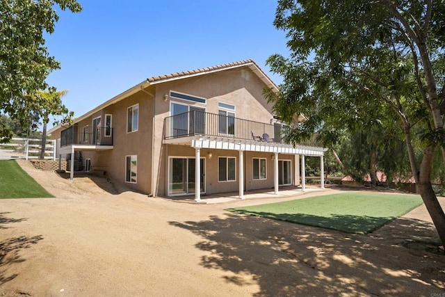 rear view of house featuring a patio, stucco siding, and a balcony