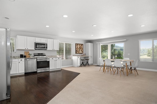 kitchen featuring baseboards, recessed lighting, white cabinetry, light stone counters, and stainless steel appliances