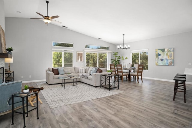 living area featuring baseboards, visible vents, wood finished floors, and ceiling fan with notable chandelier
