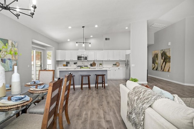 dining space featuring visible vents, baseboards, light wood finished floors, a chandelier, and recessed lighting
