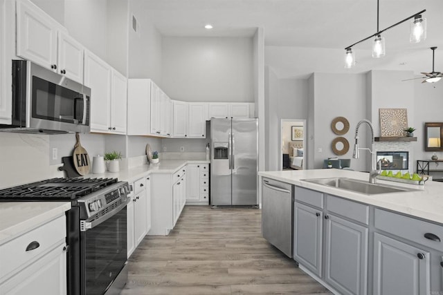 kitchen featuring a sink, white cabinets, a ceiling fan, and stainless steel appliances