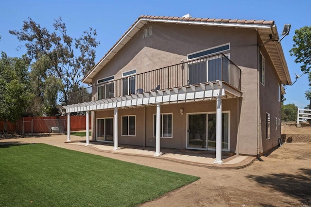 rear view of property with fence, stucco siding, a yard, and a patio area
