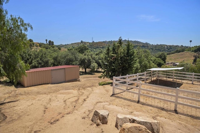 view of yard with an outdoor structure, fence, and a rural view