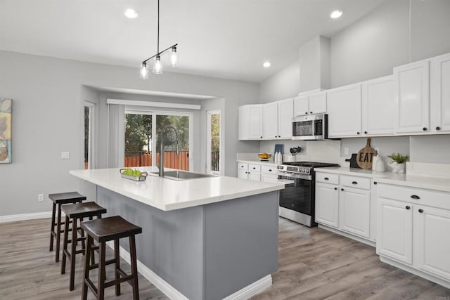 kitchen featuring white cabinets, appliances with stainless steel finishes, an island with sink, and a sink