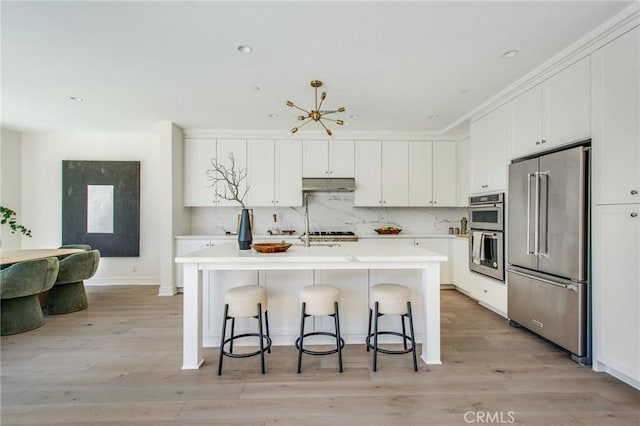 118 Tritone, Irvine, CA 92602 - kitchen featuring under cabinet range hood, a kitchen bar, light countertops, white cabinets, and appliances with stainless steel finishes