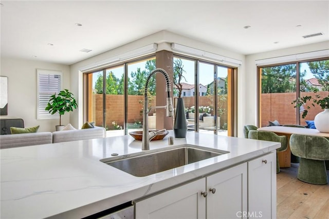 118 Tritone, Irvine, CA 92602 - kitchen featuring a sink, open floor plan, white cabinets, light wood-style floors, and light stone counters