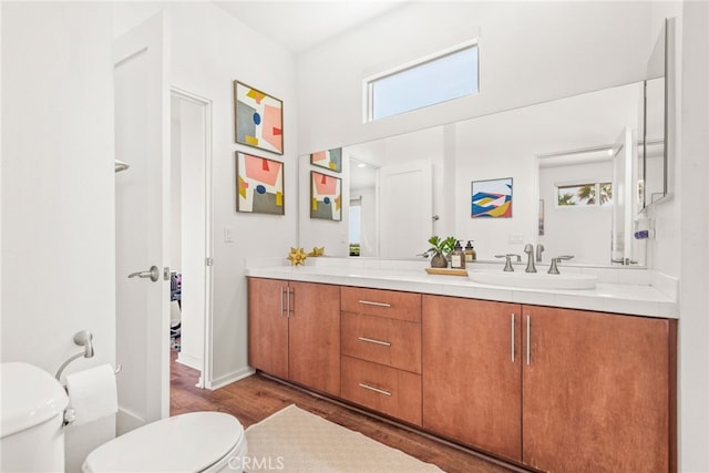 bathroom featuring toilet, wood finished floors, vanity, and baseboards