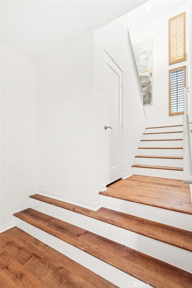 staircase featuring baseboards and wood finished floors