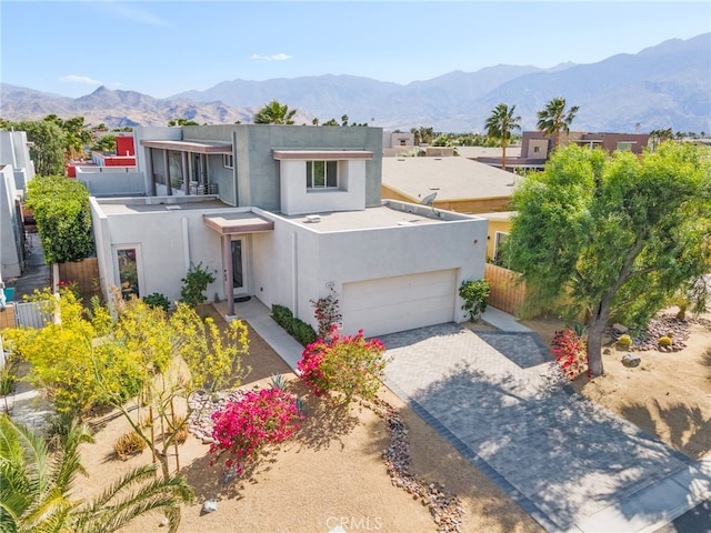view of front of home with stucco siding, decorative driveway, a mountain view, and fence
