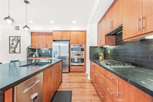 4934 Herzog Way, Palm Springs, CA 92262 - kitchen with appliances with stainless steel finishes, under cabinet range hood, backsplash, light wood-style floors, and hanging light fixtures